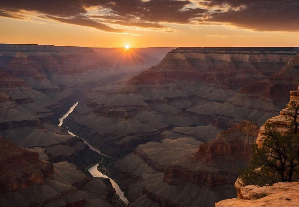 The sun sets over the vast expanse of the South Rim Grand Canyon, casting a warm glow over the rugged cliffs and winding Colorado River below